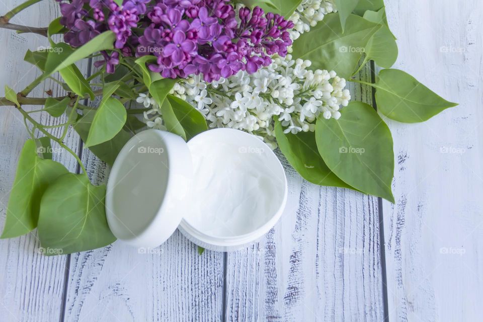 Jars with cosmetic products, beauty cosmetics in a white jar with cream and water with fragrant flowers.