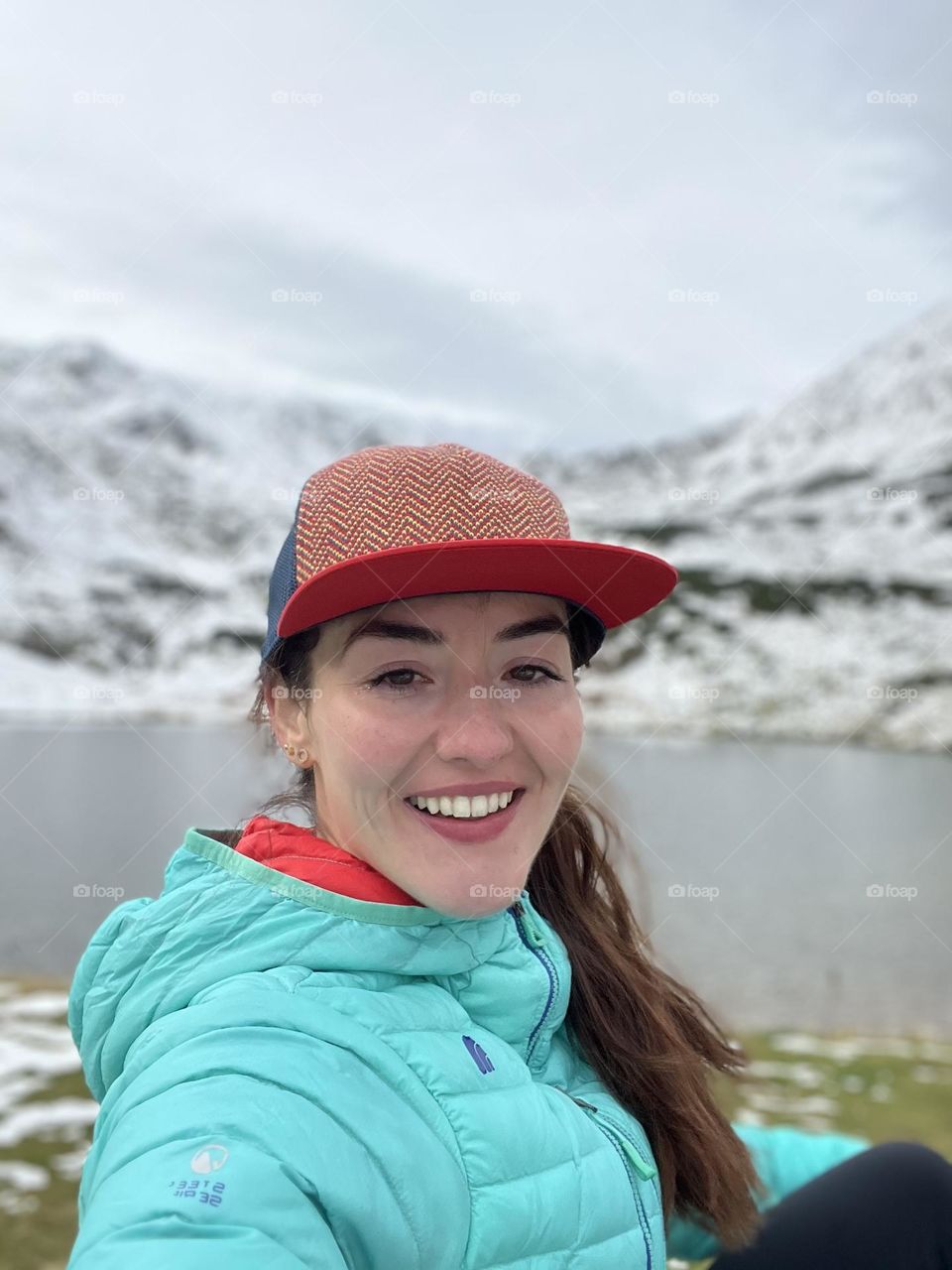 Women smiling while being on a hike in the mountains at the beginning of winter.