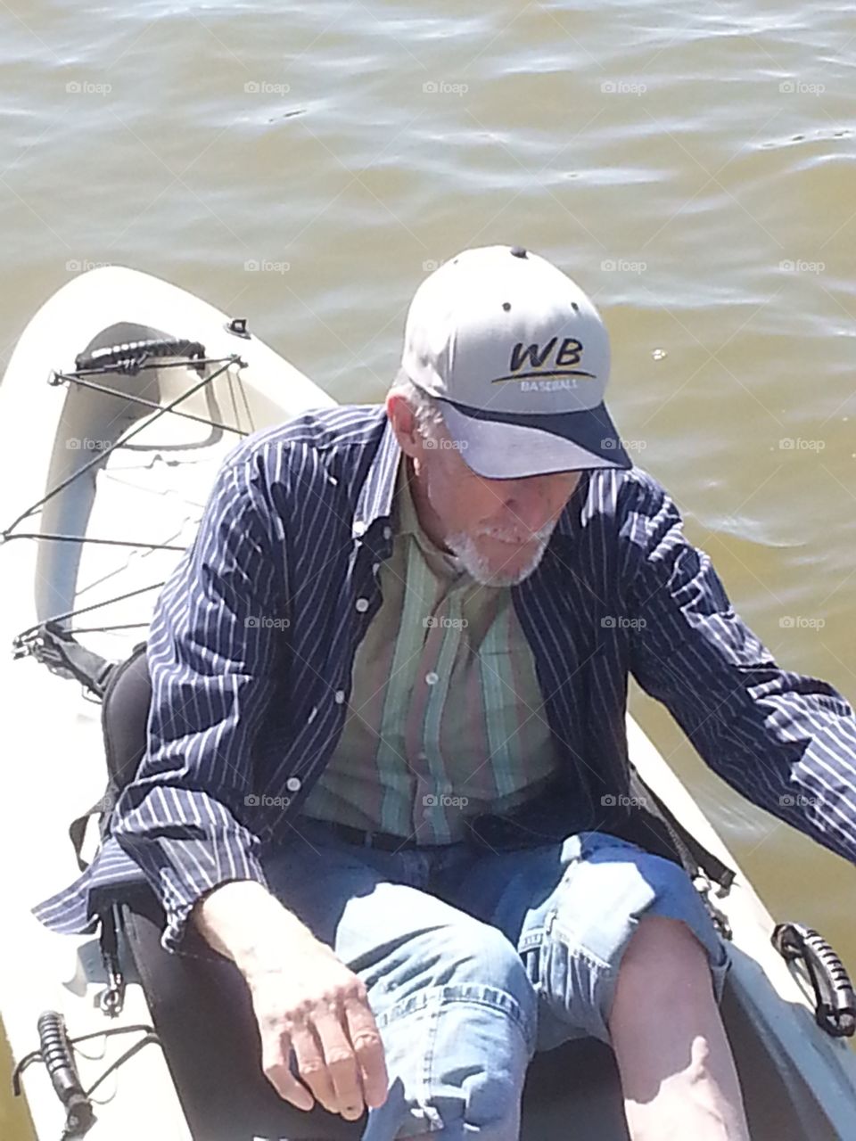 Older man in a kayak on the river just coming in to land.