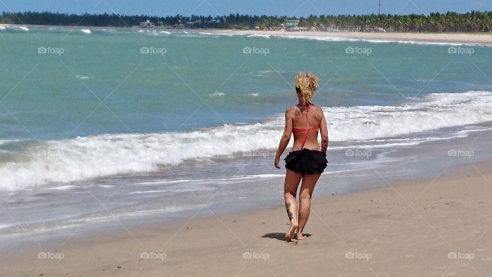 Woman walking in Porto de Gallinas beach. Brazil 