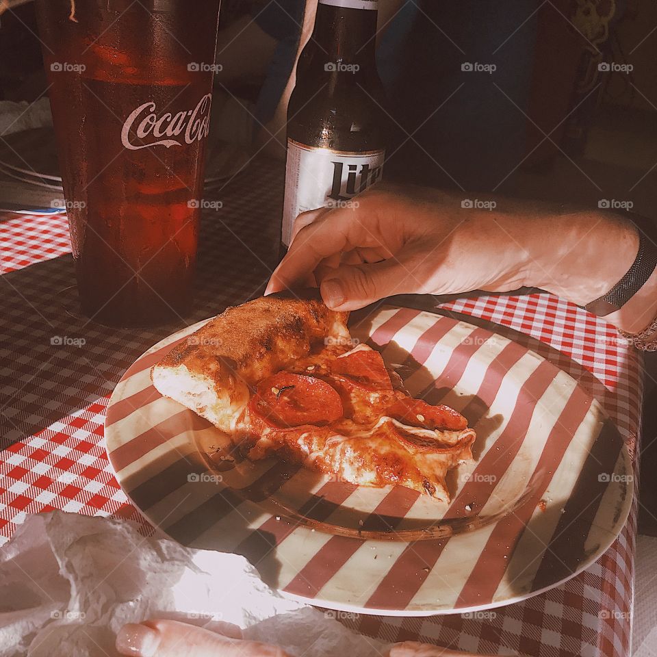 Beautiful piece of pizza next to a glass of Coca-Cola 