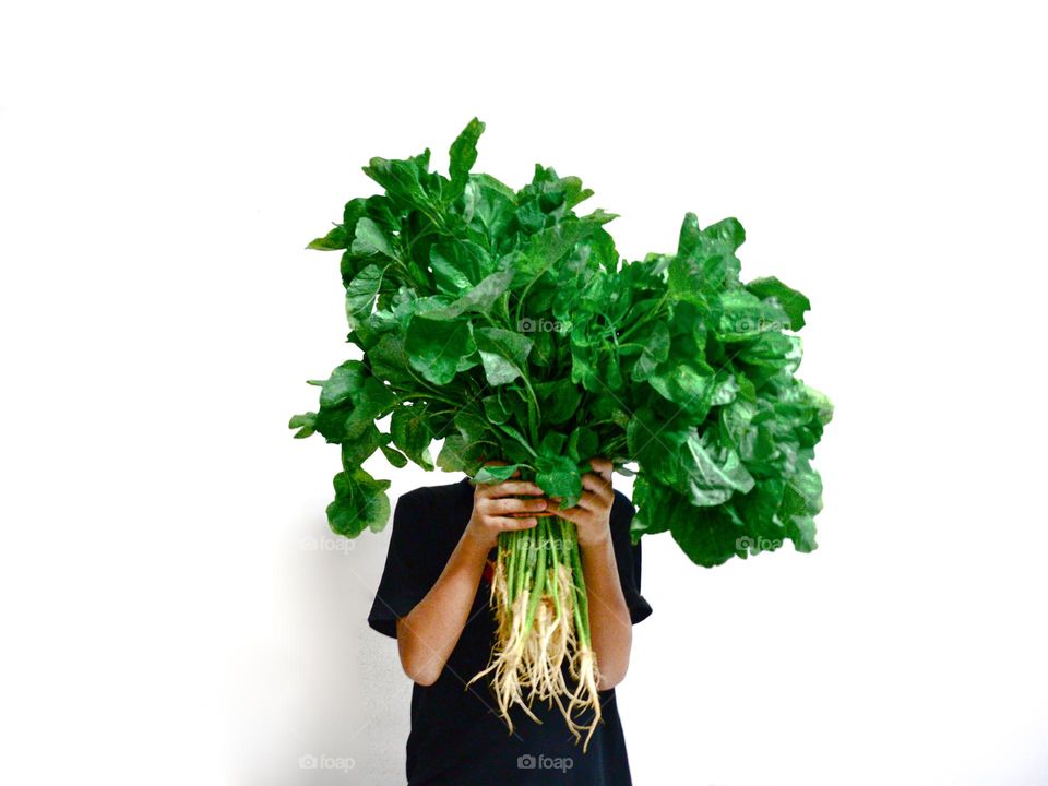 A man holding a bunch of fresh spinach against a white background