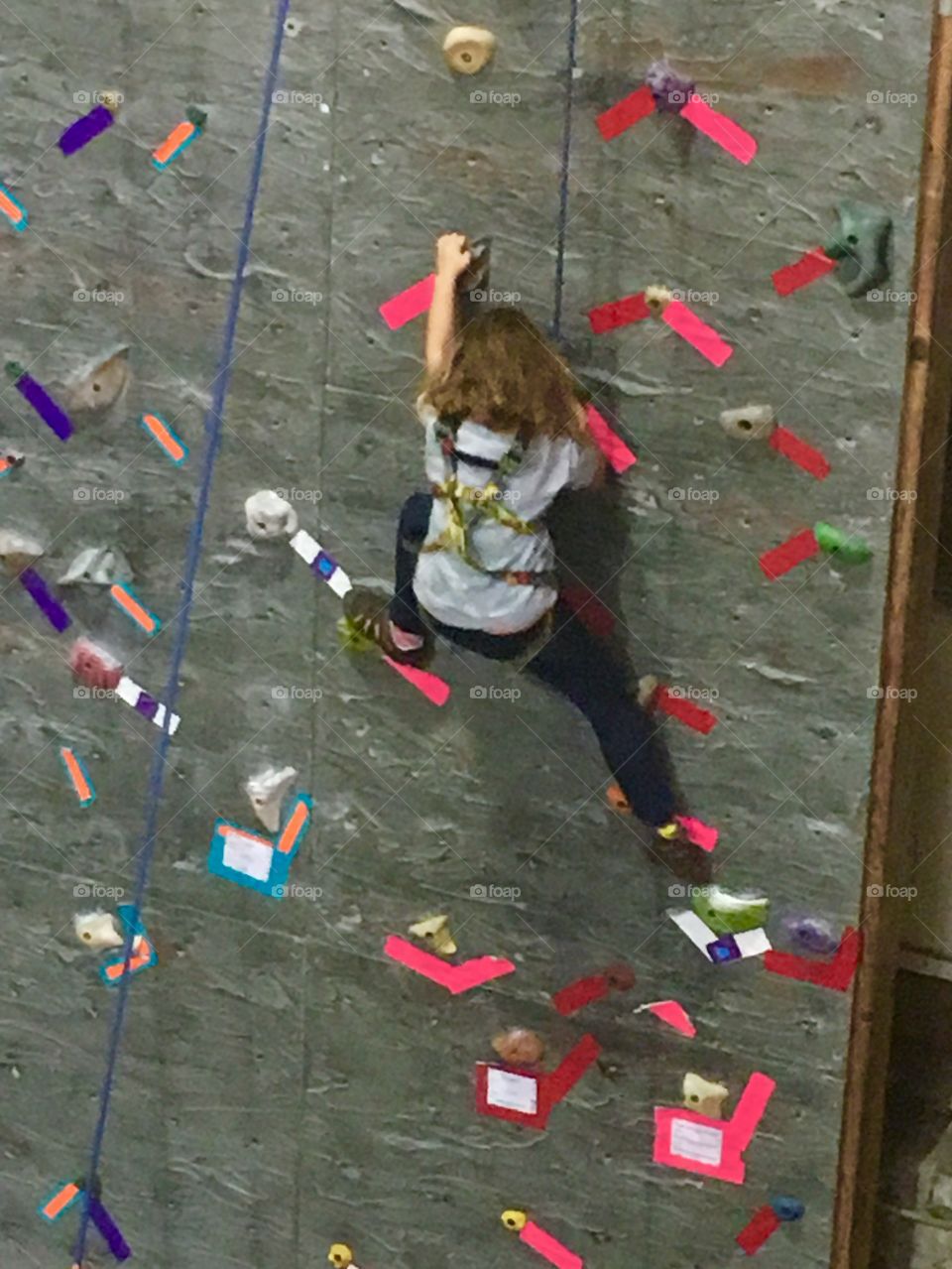 Child climbing an indoor rock wall. 