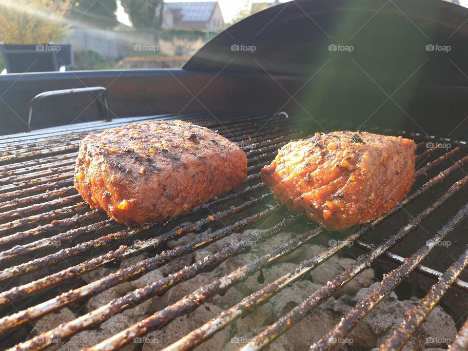 a portrait of two tasty delicious stakes lying on a hot barbecue grill on a warm summer day.