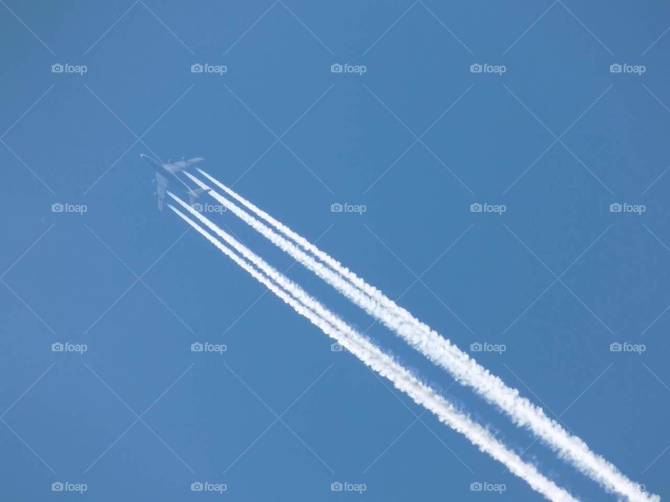 A faint plane leaving trails in the clear blue sky.