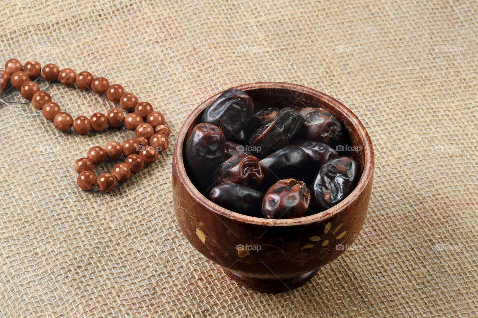 Arabian dates and rosary on burlap background