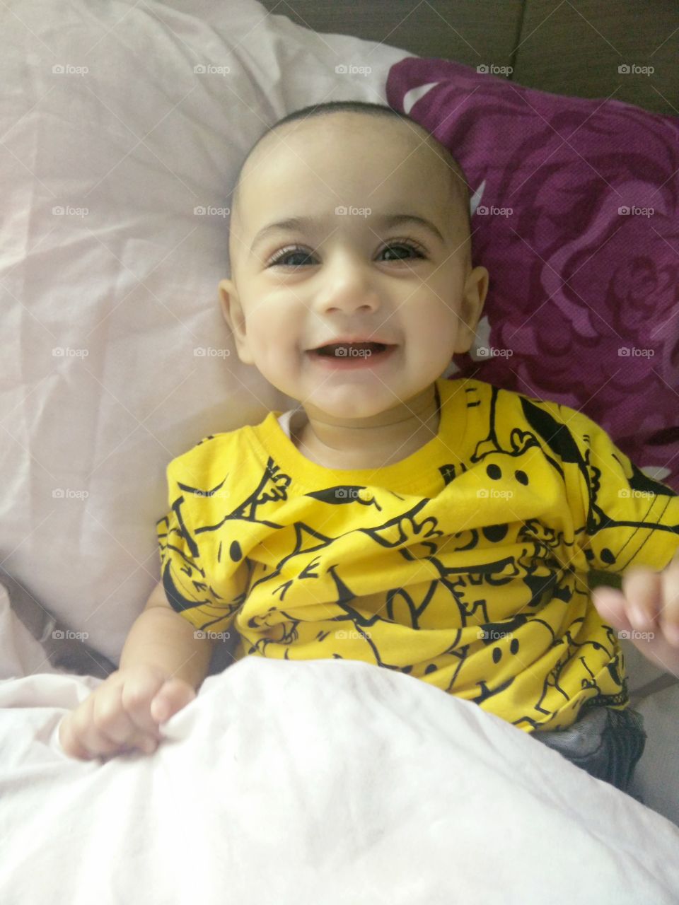 High angle view of baby boy on bed and laughing