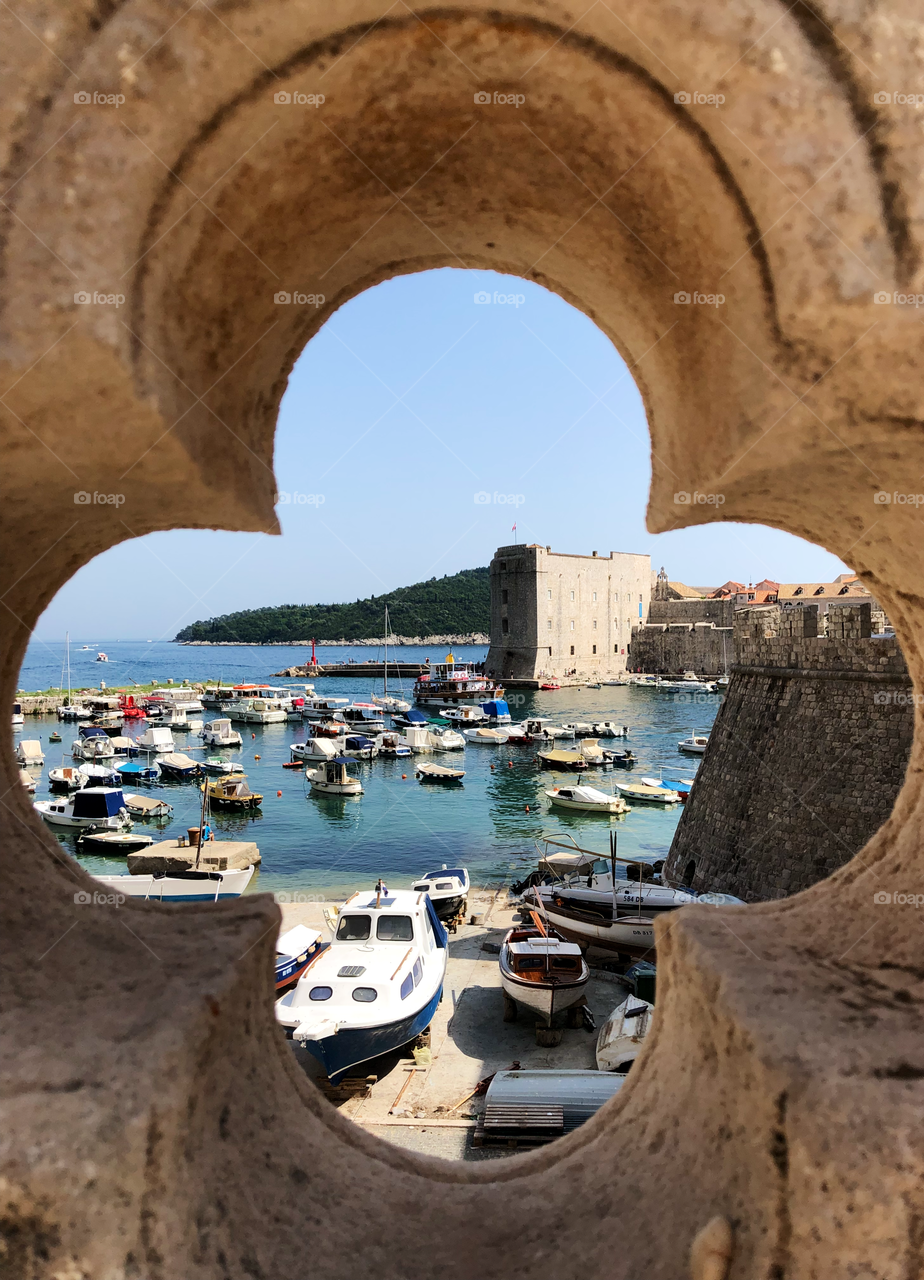 A framed view of Dubrovnik’s marina and landmark Porporela within its medieval Old City walls.