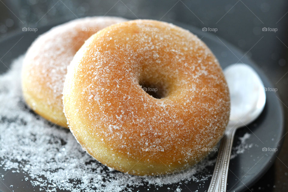 Sugar donut on black plate.