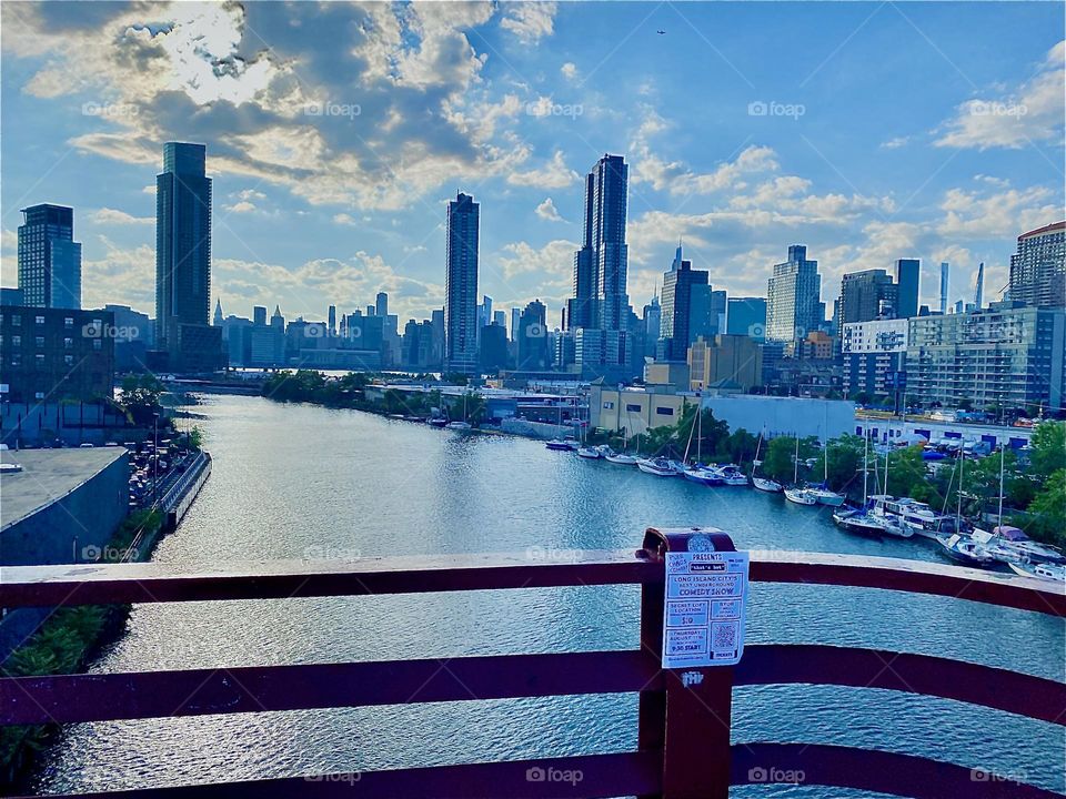 Once again there is the panoramic view from the “Pulaski Bridge” looking into the distance at “Queens” and behind it far away the “Manhattan” skyline. Barely visible on the right is “Greenpoint”, Bklyn. 2022. Hypnotic Productions