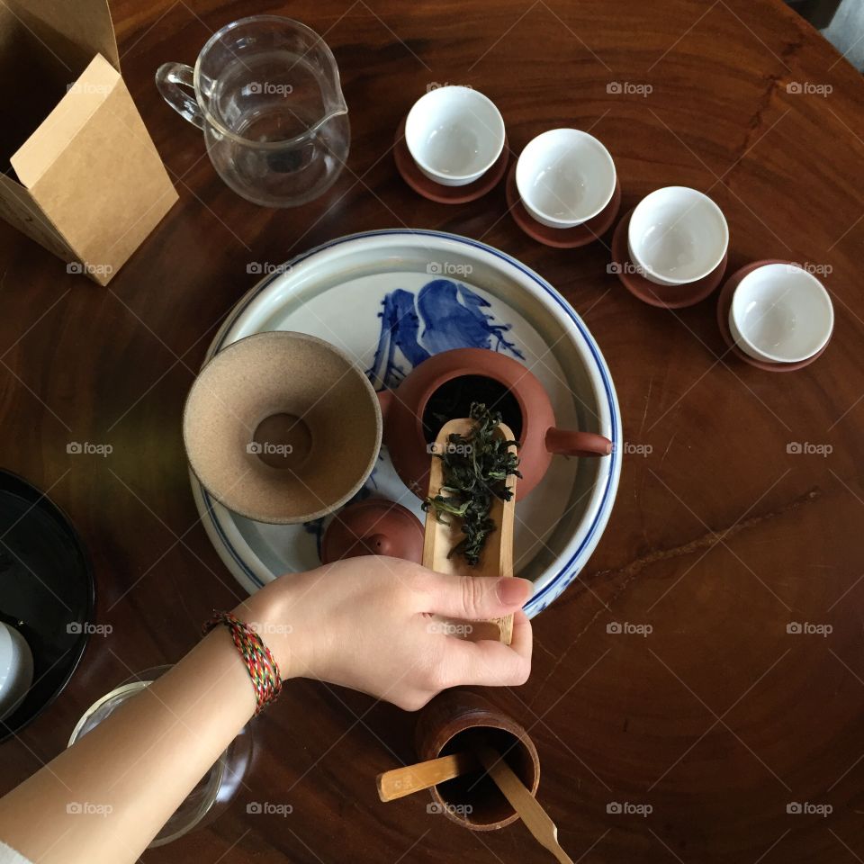 A person putting tea leaves in the tea pot