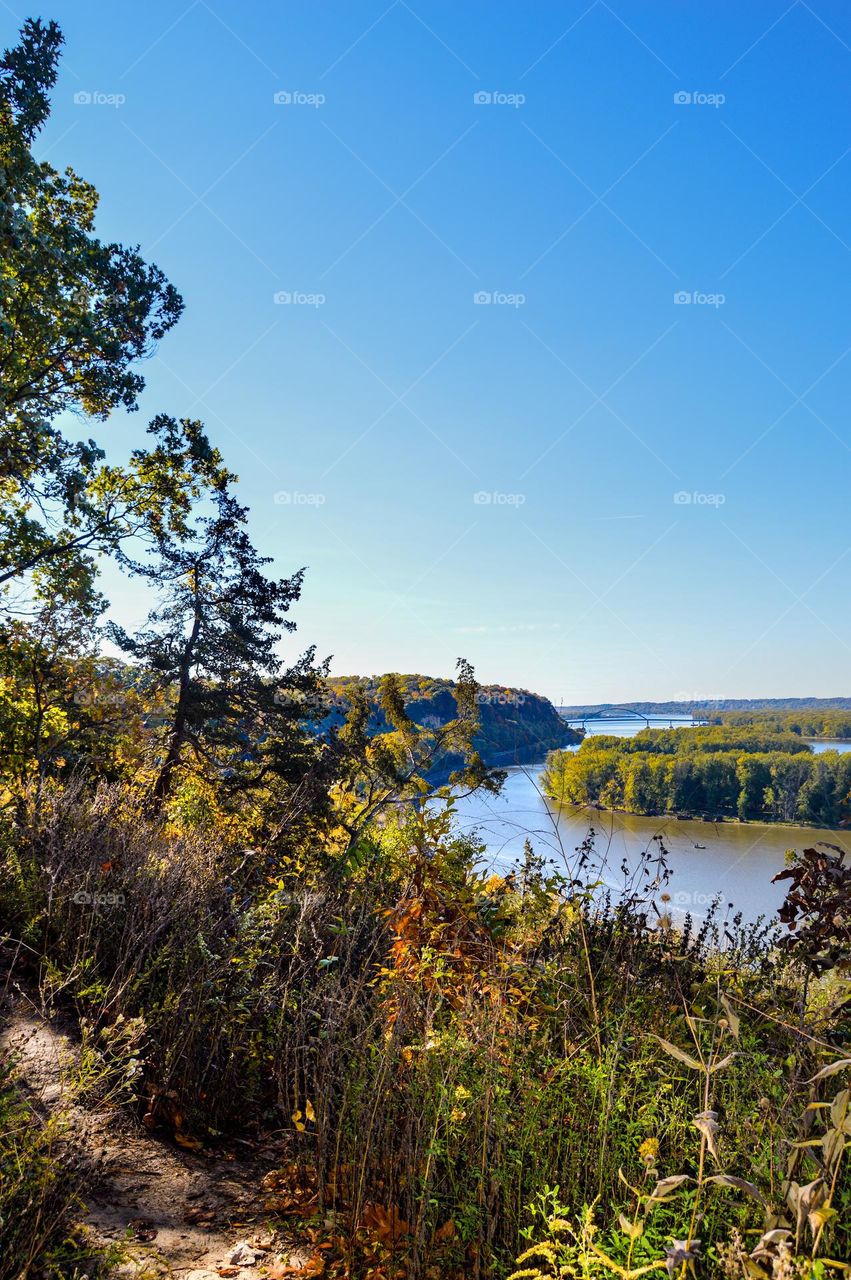 a daytime landscape view of the Mississippi River from a lookout on a hiking trail on top of an extremely high bluff at the Palisades state park in Savanna, Illinois.