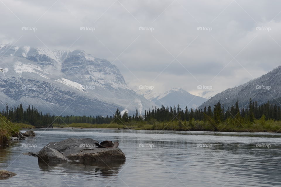 Canada Rocky Mountains , cowboy hat on a rock in remote alpine lake 