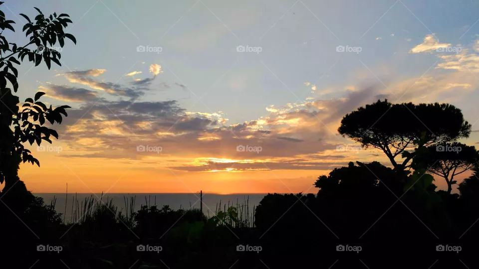 The orange tones of the summer sunset in the village of Cuotto on the Italian island of Ischia