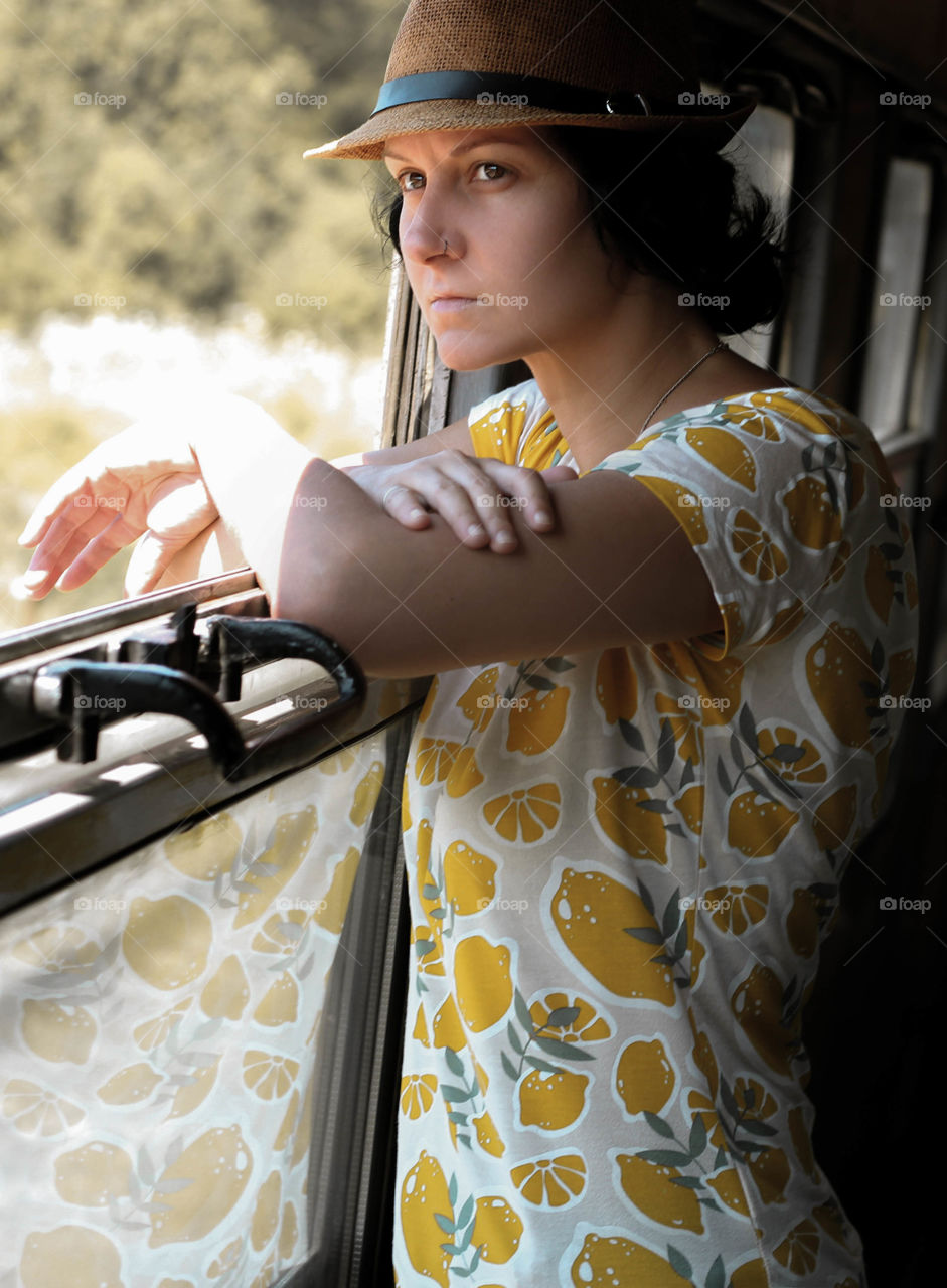 Traveling by train, young woman with a hat on the train window, indoors