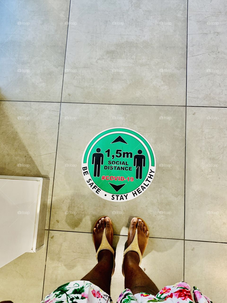 Green round sticker marking the distance between clients in a warehouse. It indicates that clients should stand 1.5M away from each other. 