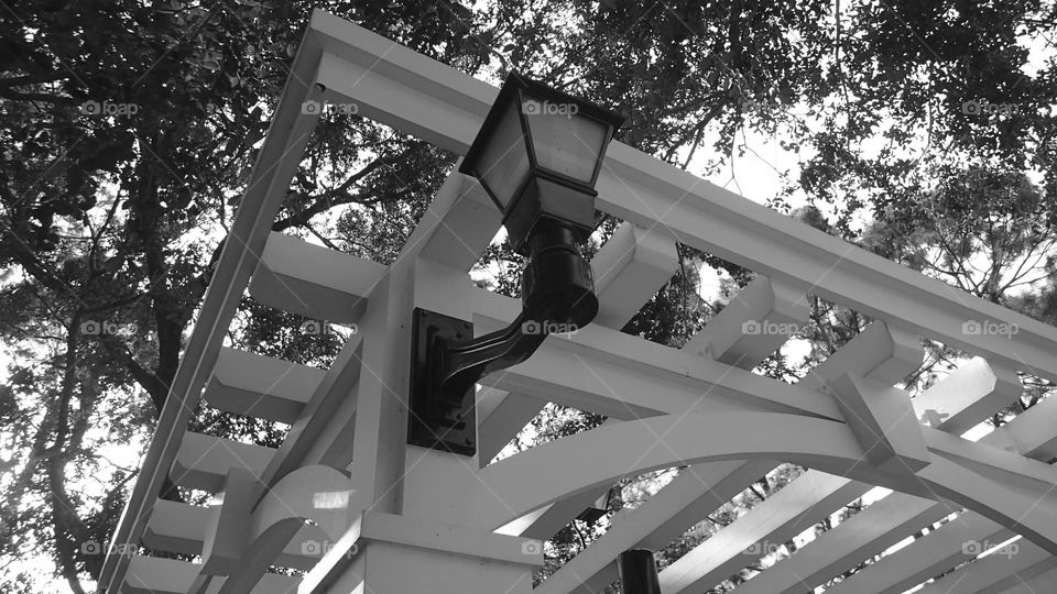 Architectural lines of backyard white wooden gazebo with black metal coach light 