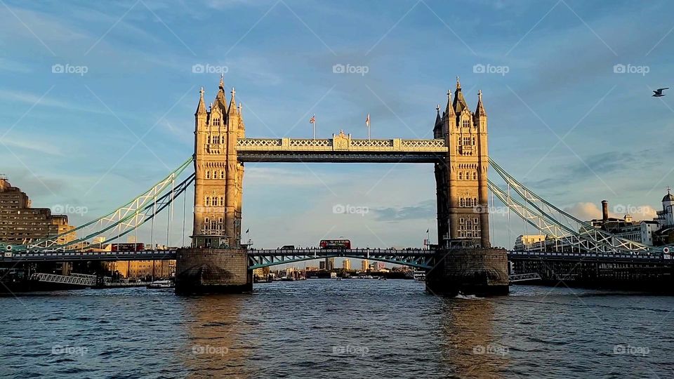 View from the Thames River of the Tower Bridge in London England with a classic double decker bus.