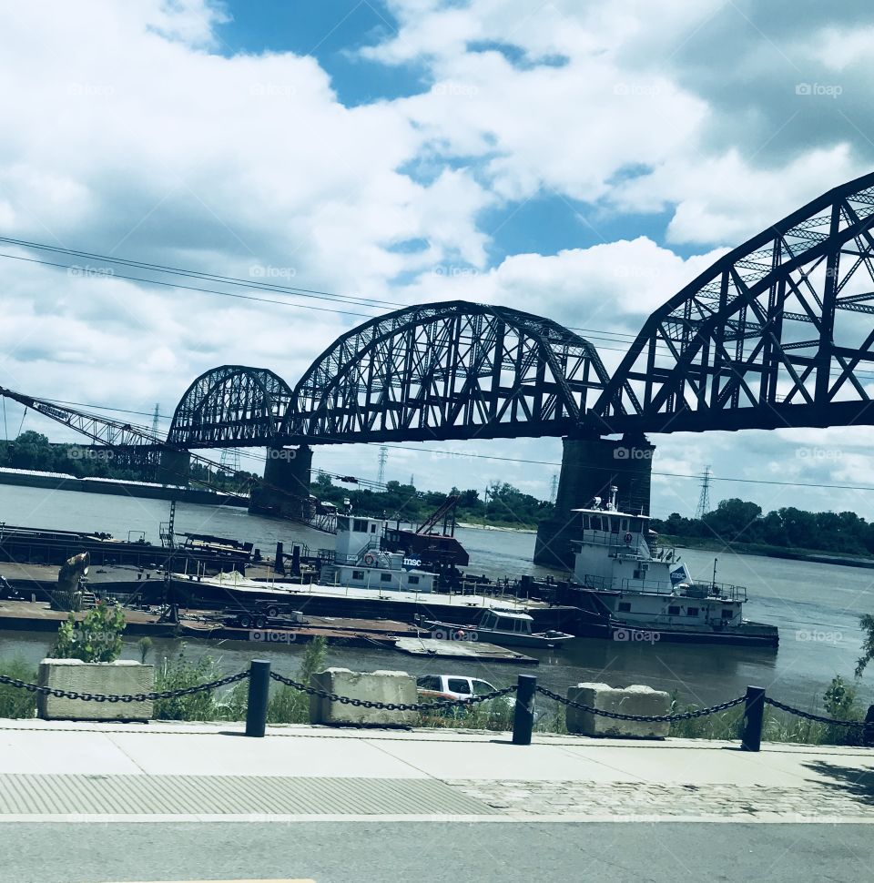 A view from our Charter Bus of a very cool bridge over the river in St. Louis, MO with a boat passing below. 