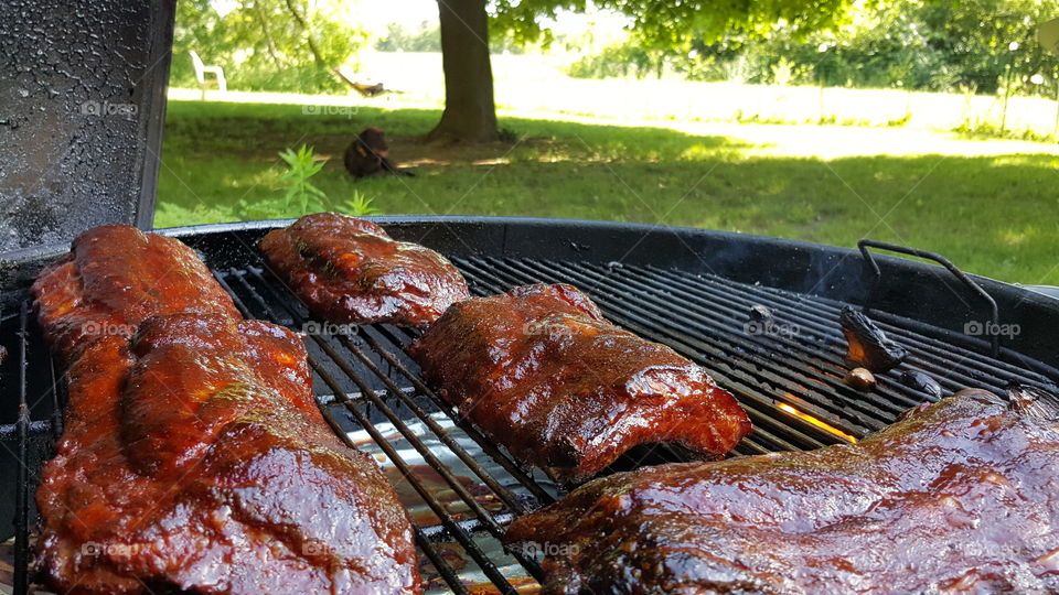 half racks of ribs sitting on charcoal grill grate