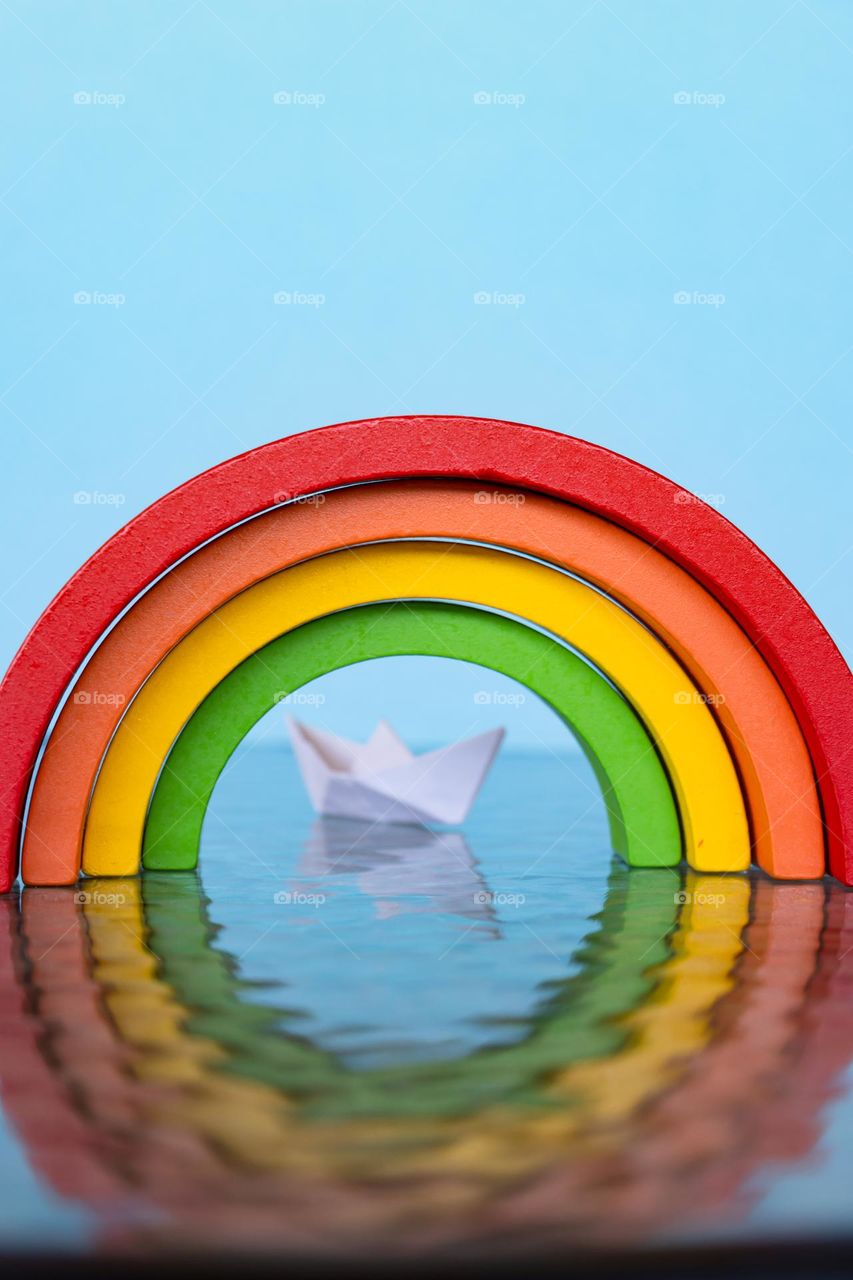 Wooden rainbow over paper boat