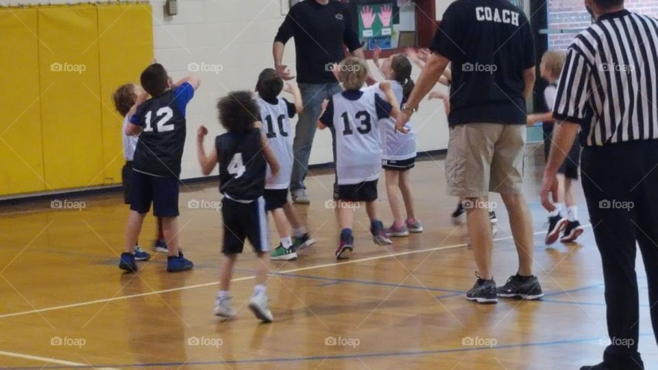 Children looking for the rebound in a basketball game