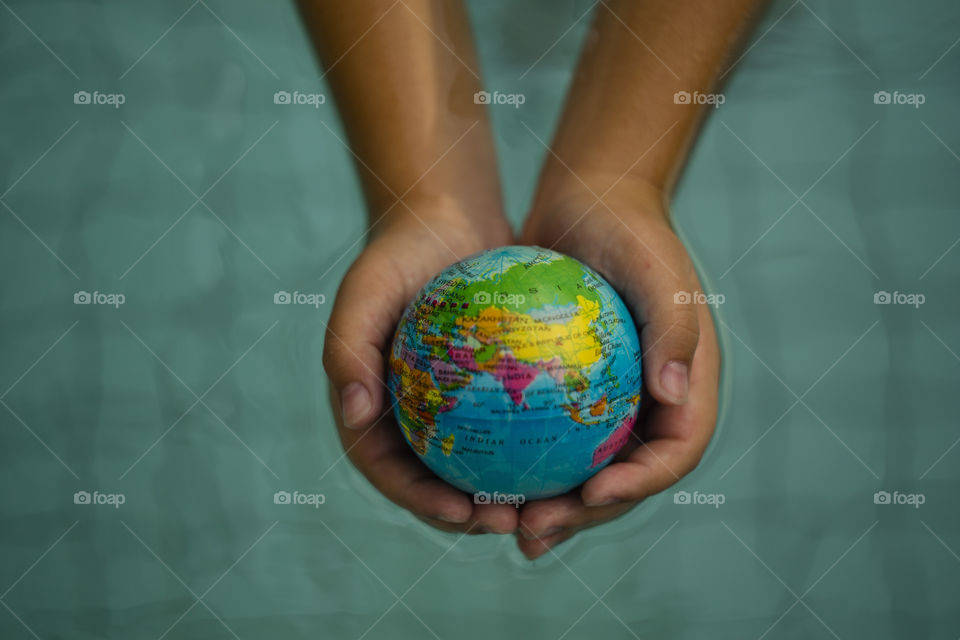 overhead looking down on hands holding world sphere, showing Asian continent