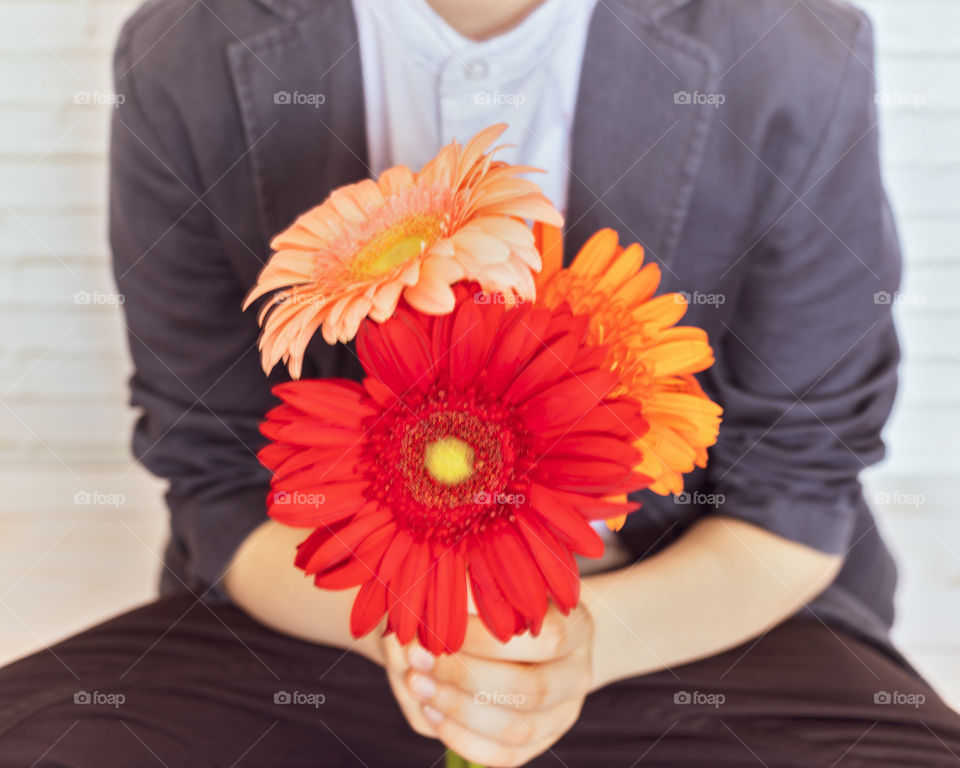 Blurred composition with a schoolboy with a bouquet of colorful gerberas in his hands. The concept of the end or beginning of the school year and gratitude to the teacher