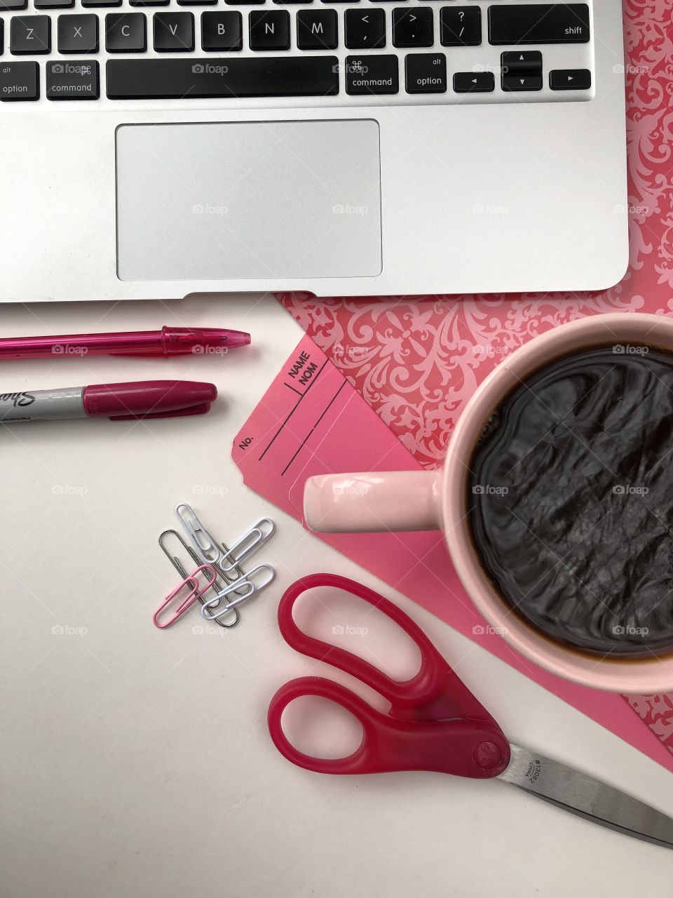 Pink themed flat lay of office workspace with a cup of coffee and some white space