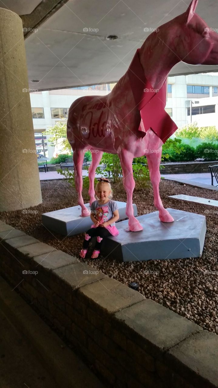 Little girl sitting near the statue horse