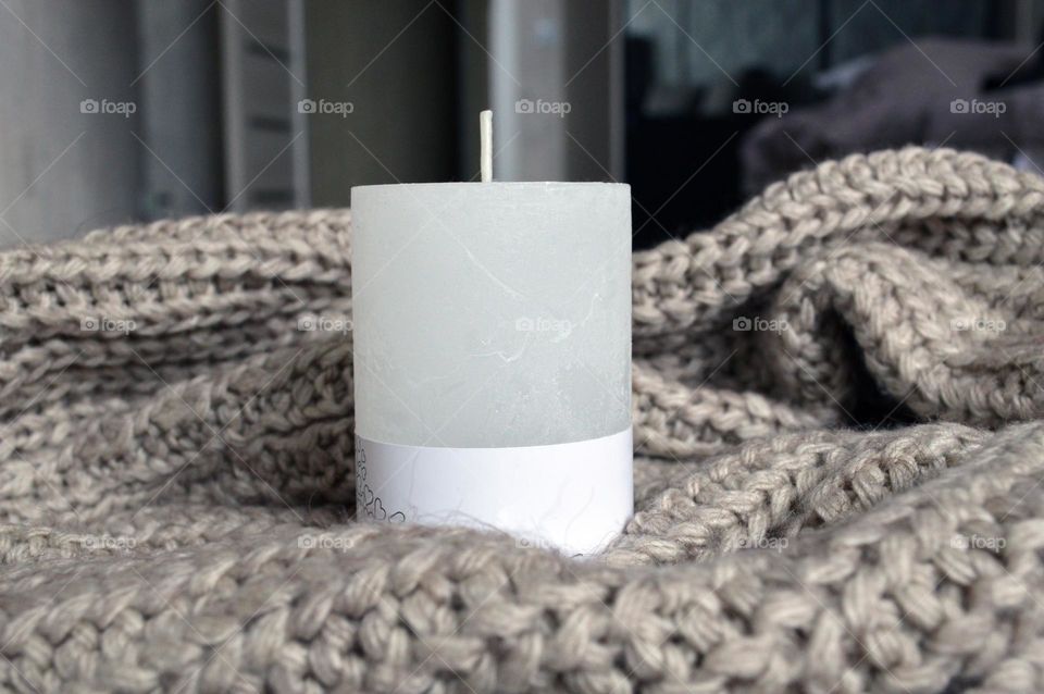 White candle on a knitted background