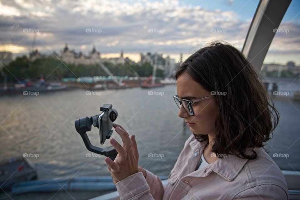 A teenage girl records video with her smartphone on a gimbal 