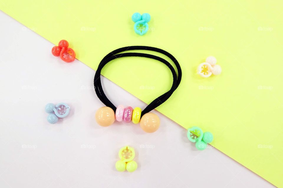 Black Rubber Band with Bead Fashion Accessories. Hair Elastic Band with Free Space. Black Hair Band with Colorful Hair Clip Isolated on Pink and Yellow Background Great for Any Use.