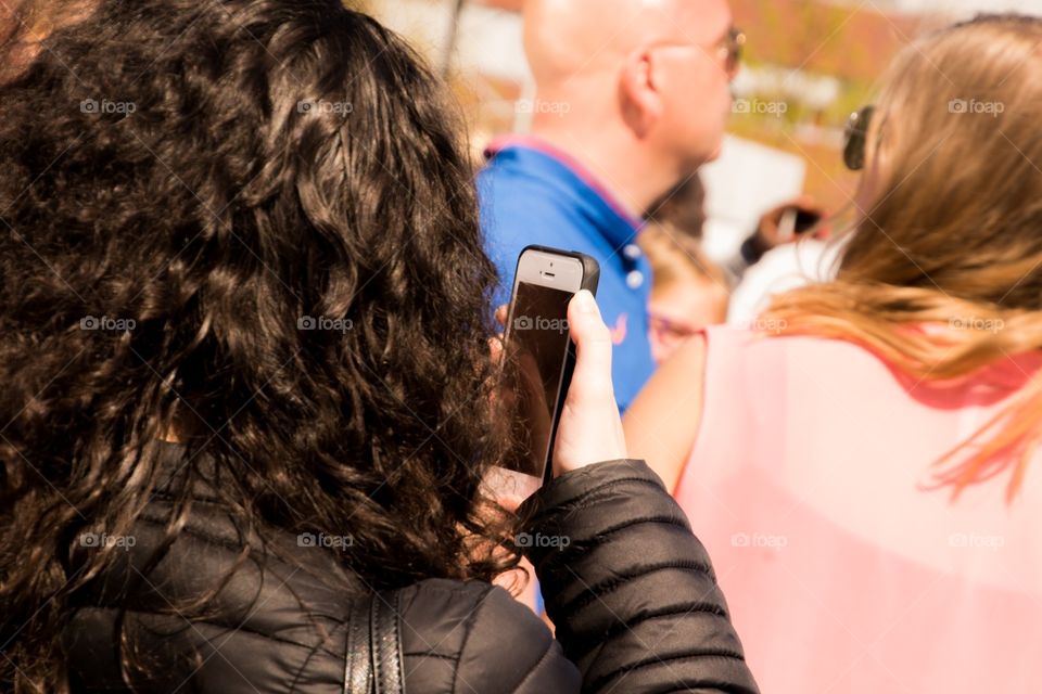 A girl with dark hair is checking her phone at a festival
