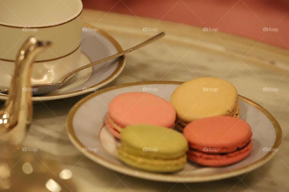 Colorful macaroons in a plate with cup of tea on tabletop 