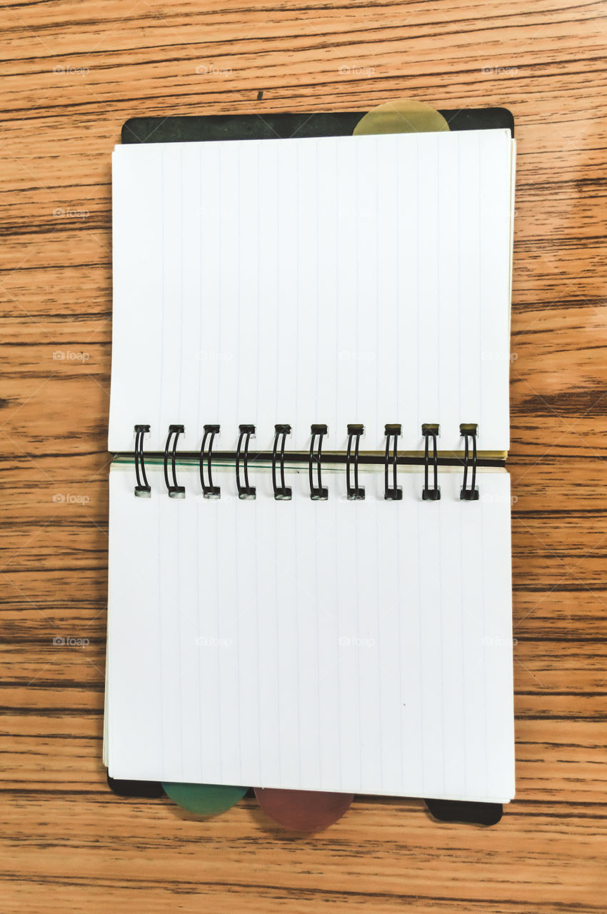 Blank empty notepad on a wood table. Top view image of open pocket planner notebook with empty pages ready for adding text or mockup.