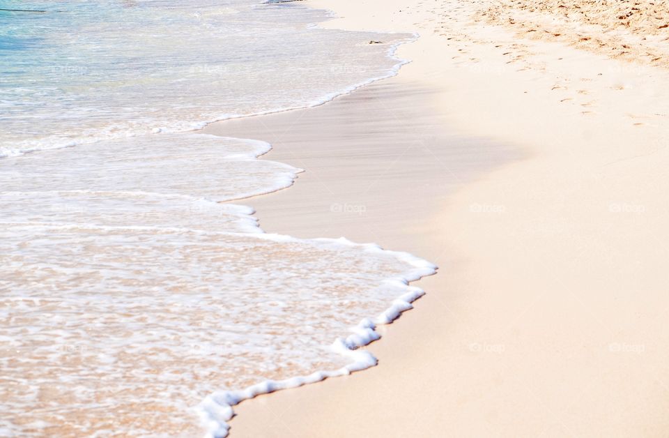 Clear beautiful waves roll over the white sand beach of Grand Turk. 