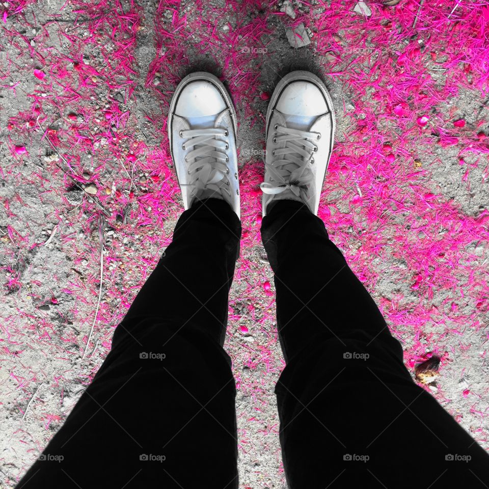 Feet in leather sneaker on pavement background, top view