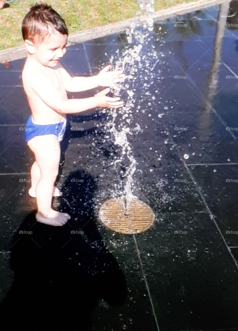 Little boy playing with a fountain