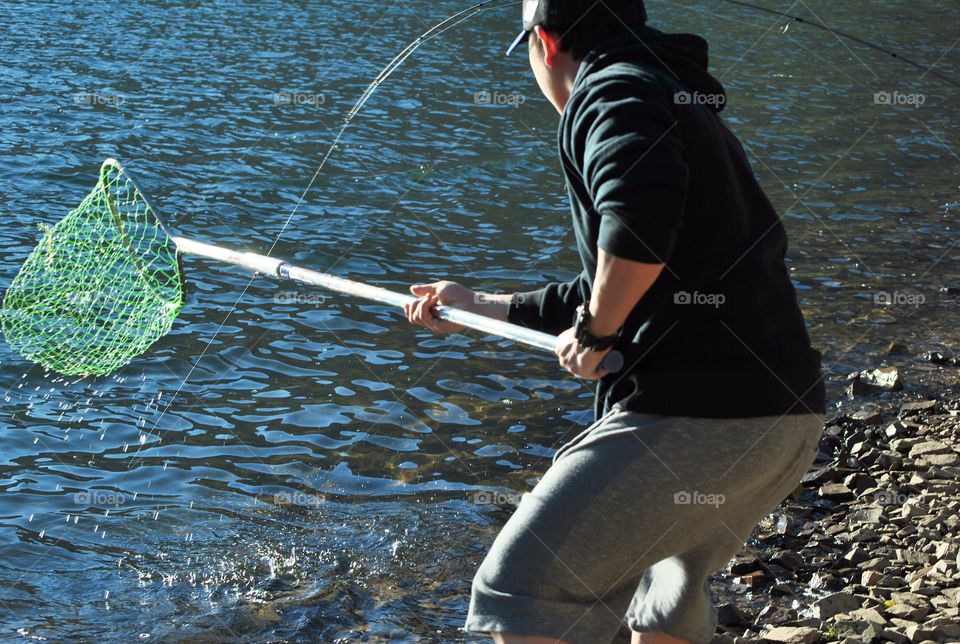 Catching a fish with net by the lake