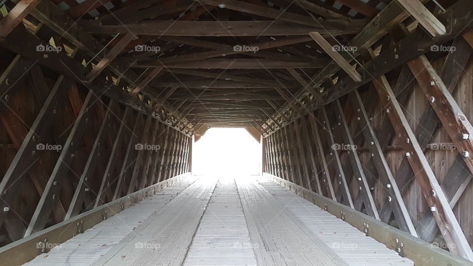 Inside view of a wooden covered bridge with an dazzling light in background. Vermont. USA.