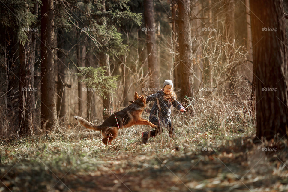 Girl walking with German shepherd puppy in a spring forest 