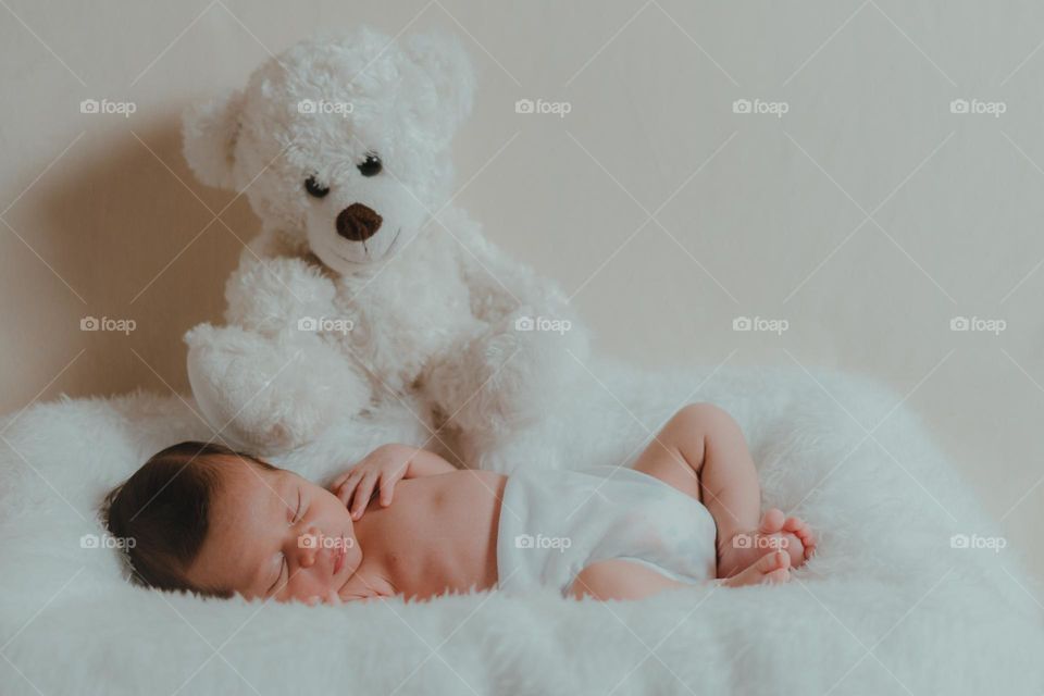Baby newborn sleeping and transmitting peace and serenity, next to a big teddy bear