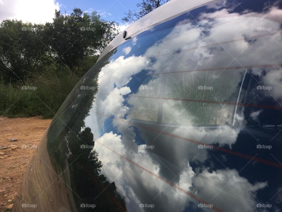 Clouds reflected on the car windshield. 