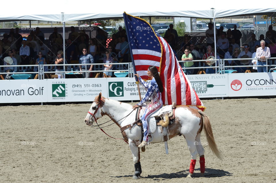 The opening ceremony of the rodeo featuring the a girl on horseback holding a huge American Flag!!