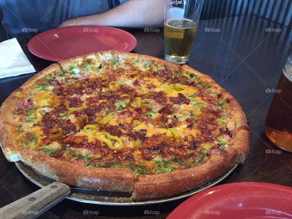 This pizza has a pesto sauce base with chicken, bacon, banana peppers and jerk sauce. Yum.