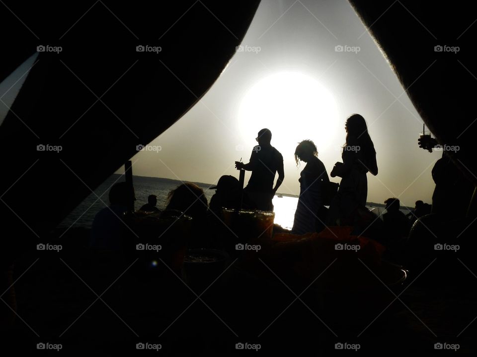 silhouette of people in a party on the beach taken under legs