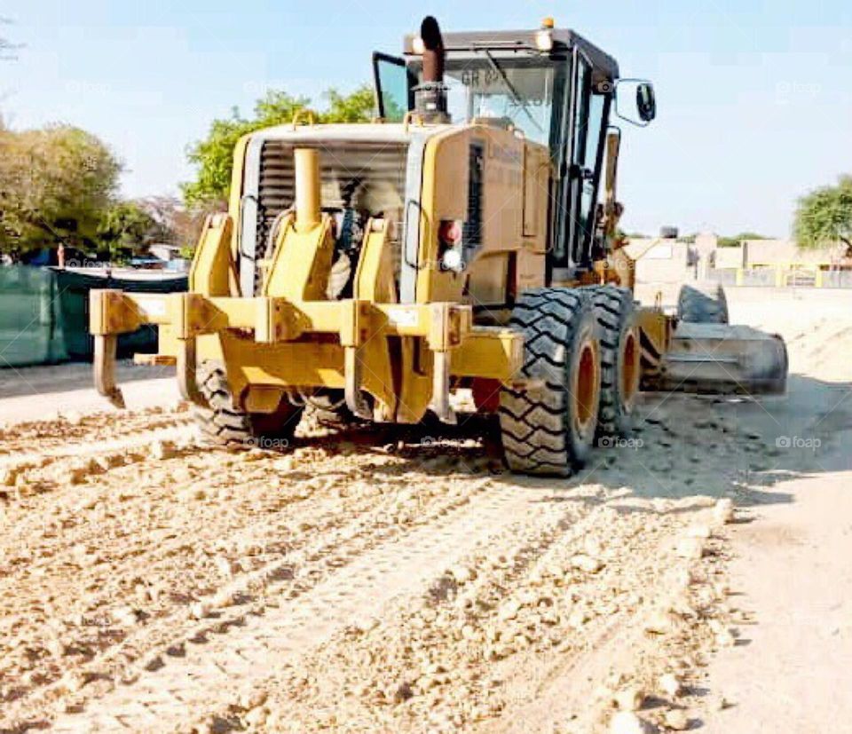 Grader , the heavy duty machine used at construction of roads mostly. But here it was used at a site before installing interlock .