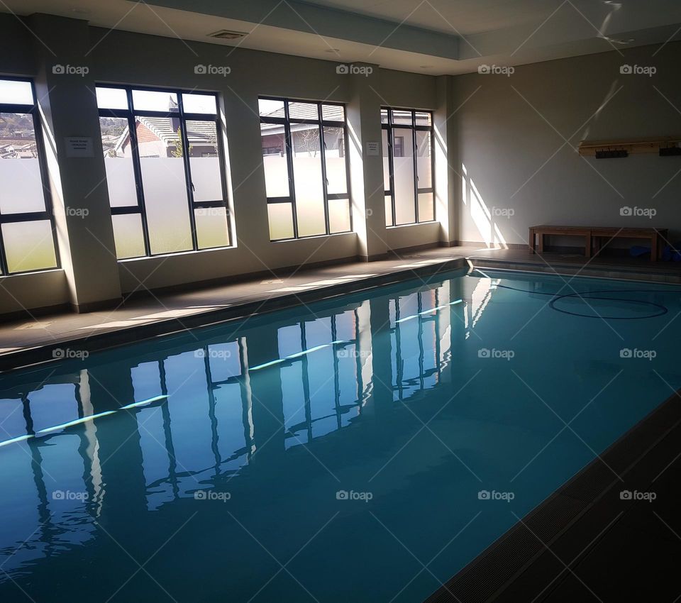 indoor swimming pool with rectangular windows and reflection.