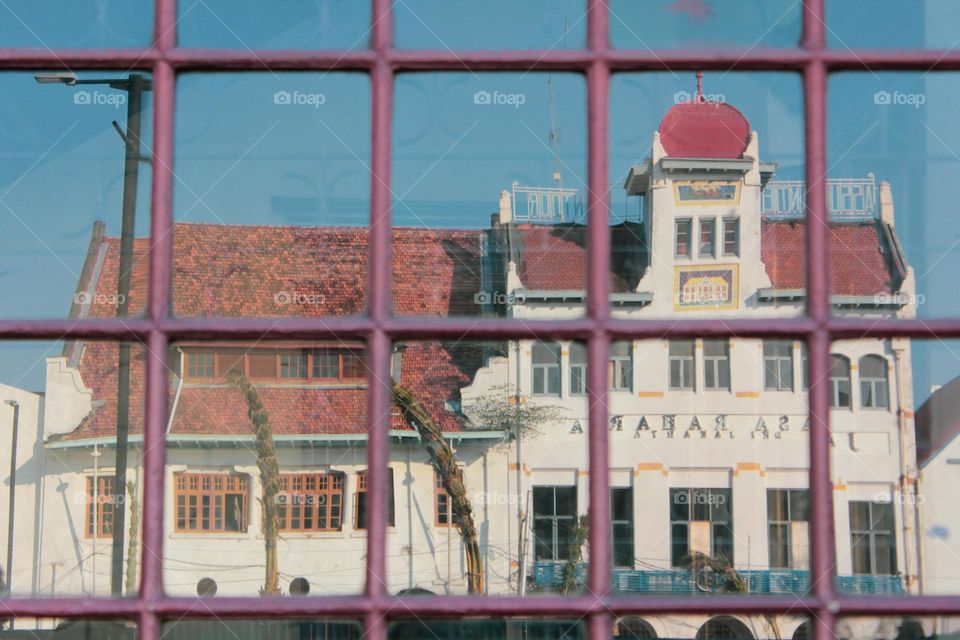 Portrait reflection of a building from the Dutch colonial heritage on a building window framed by wooden windows, namely the European-style maritime museum, Jakarta, Indonesia.